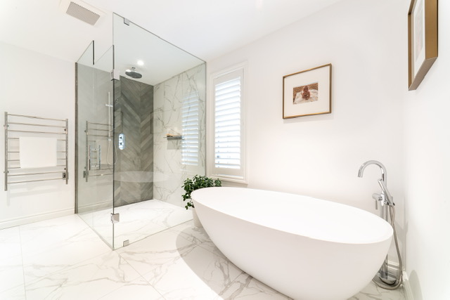 This bathroom features a white, circular tub, a glass shower, nickel-finished fixtures and two images hanging on the wall. 